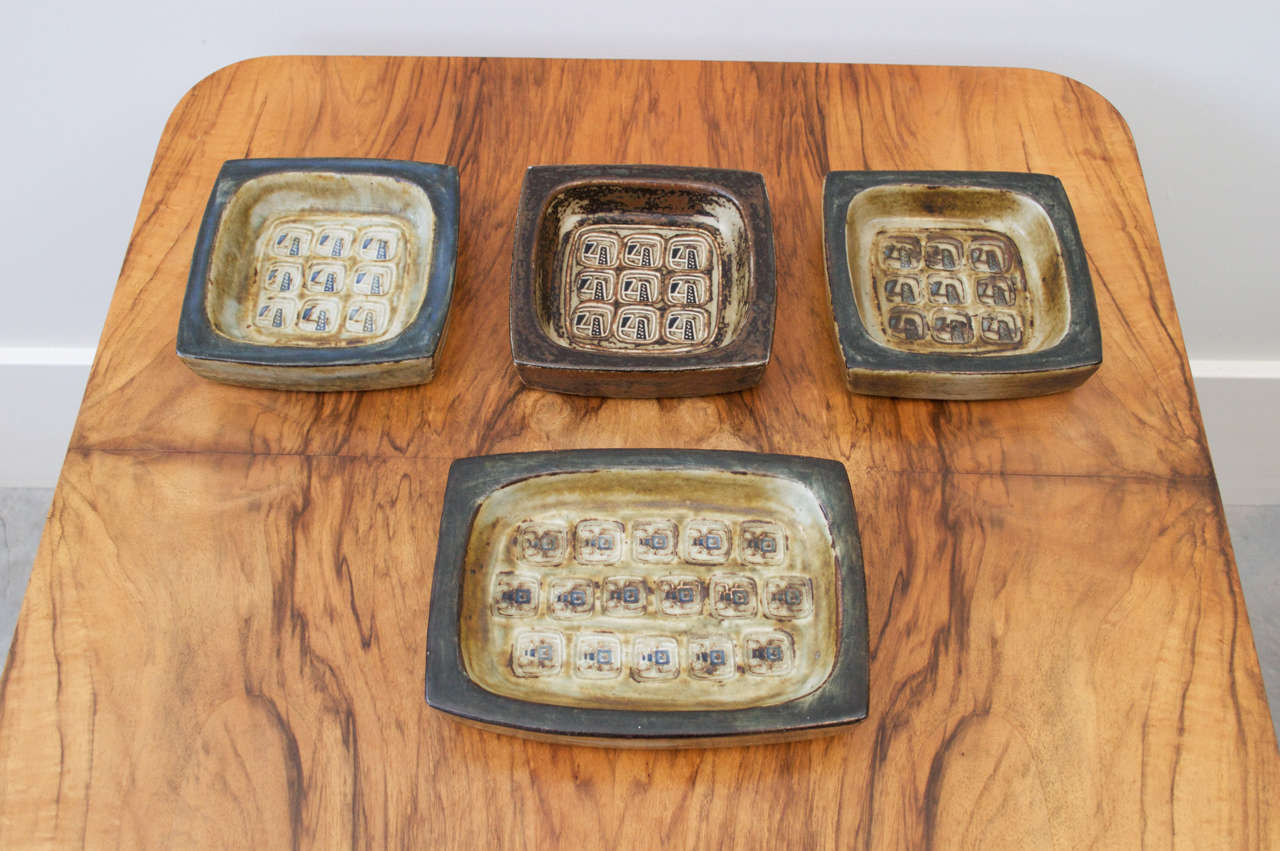 Four Stoneware dishes by Jørgen Mogensen, son of designer Borge Mogenson. Made between 1969-1974. Various sizes in earth tone glazes with stamped designs in relief. Would look very nice in a straight line down a mahogany dining room table. 
In