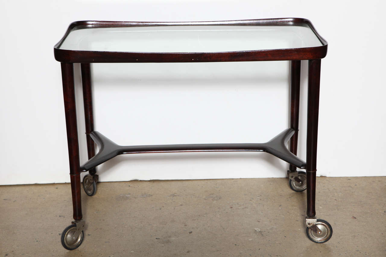 Italian Modern sculpted solid Rosewood and Glass Mobile Cart, Made in Italy. Featuring an open smooth sculpted rectangular Rosewood framework with rounded lipped surface corners, inset glass top, moulded lower Rosewood support on four original