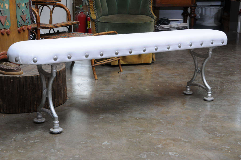 Pair of unusual studded, upholstered benches with wrought iron bases.