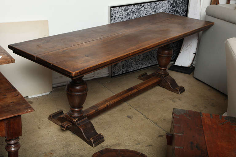 A long dark wood console table with twin urn pedestals and stretcher.