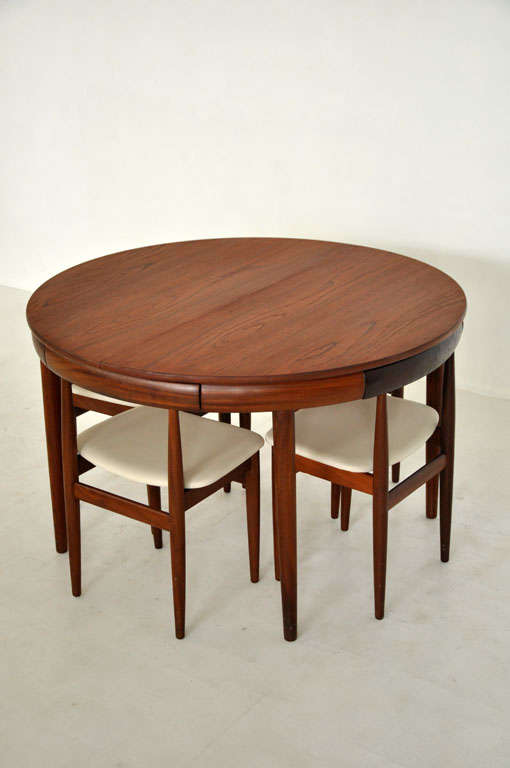 Teak dining set by Hans Olsen for Frem Rojle.  Table has fold out leaf.  Hide away chairs store within the table skirt.  Newly upholstered in cream leather.  Labeled 