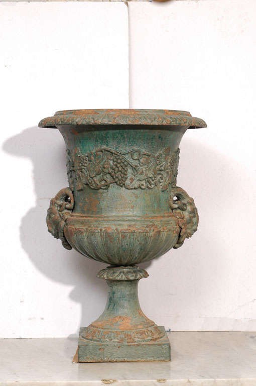 Green painted medici urn, with grape vine decoration and lamb head handles.