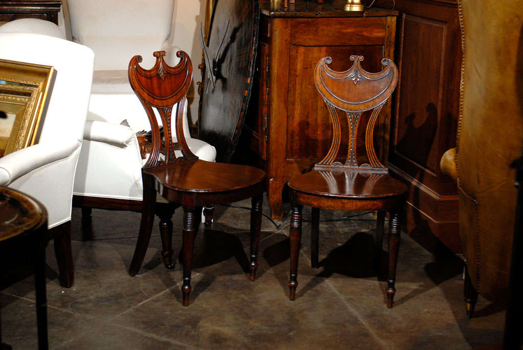 Cette exquise paire de chaises de salon anglaises inclinées présente des dossiers moulés à gorgettes ornés de délicates rosettes, de volutes et de motifs feuillus, au sommet d'éclisses percées. Les sièges arrondis reposent sur deux pieds tournés à