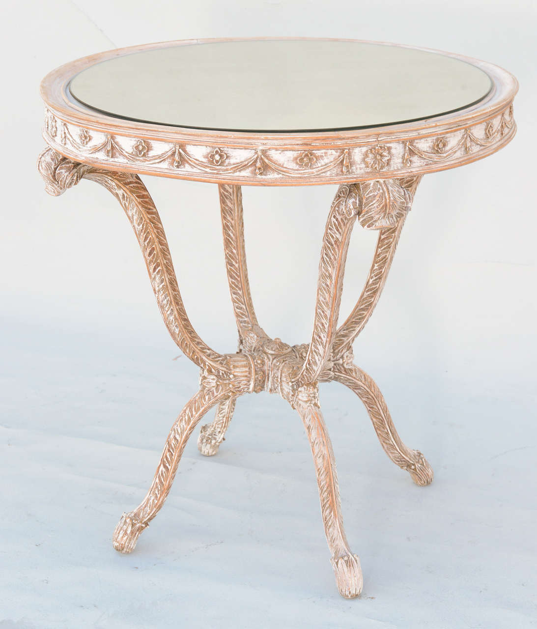 Round table, with pickled finish, having a round mirrored top, its apron carved with rosettes and swags, raised on plume-form legs.

Stock ID: D3490