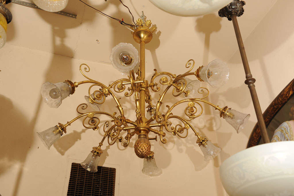 This unusual chandelier will give all the light you'll ever need. With twelve arms pointing in all directions, it's quite a nice fixture. All the bronze work is original gilt and the shades are period to the fixture and have fleur de lys patterns