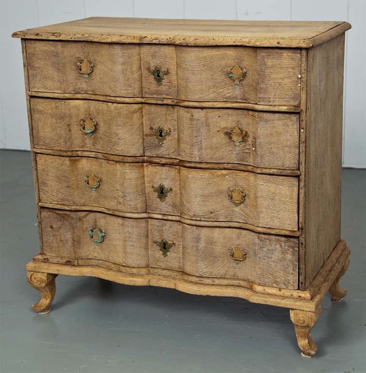 A four-drawer carved oak chest with an serpentine form face.
Original hardware and key.