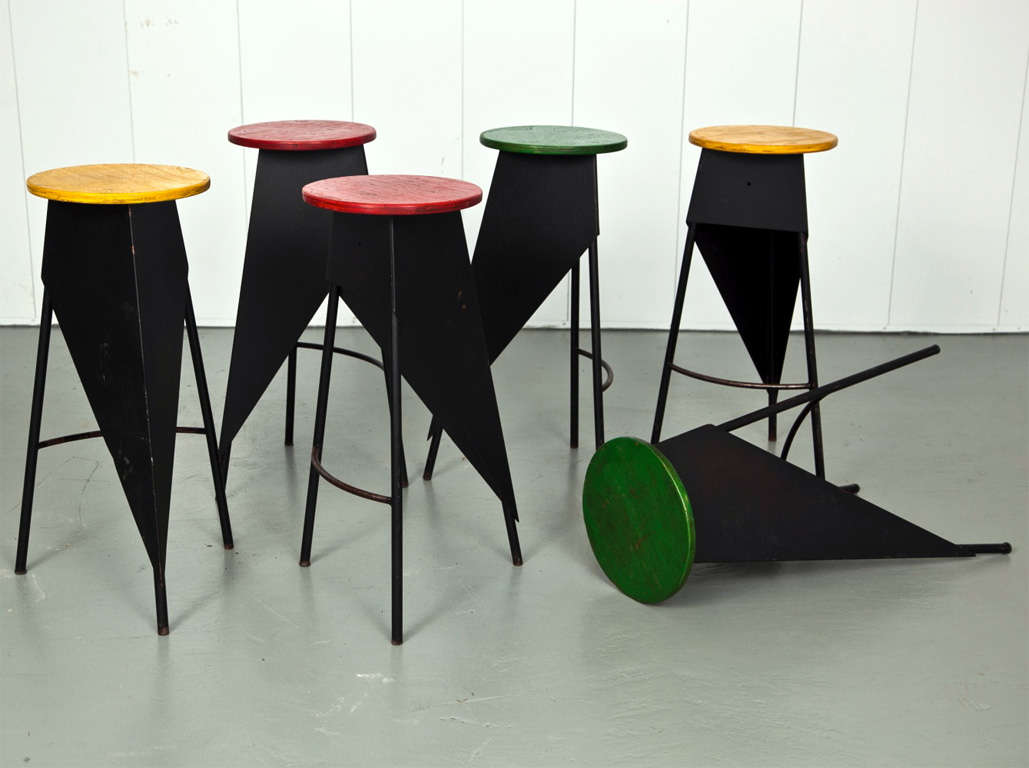 Black Iron based stools with a three-legged triangular design and painted wood seats