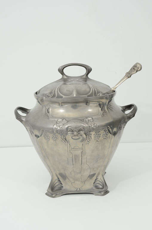 A German Art Nouveau punchbowl cast with Bacchus masks and grape motifs with matching cover, silver plated pewter ladle and original crystal liner.<br />
Engelbert Kayser (1840-1911) established his own pewter design workshop and atelier in
