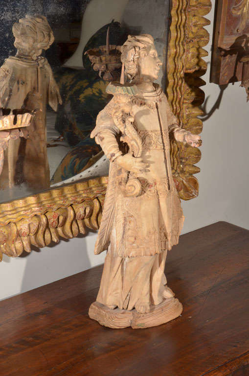 Figure magnifiquement sculptée portant une torche, vêtue de vêtements détaillés avec de la dentelle et des franges sculptées. Des détails incroyables.
