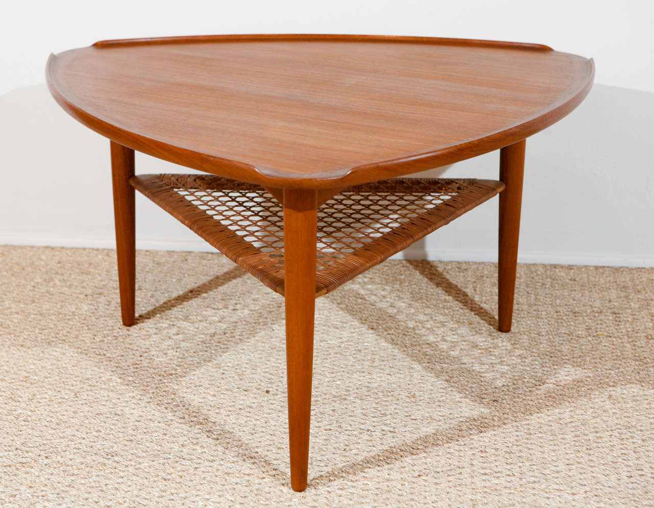 Original Danish Modern table.  Identifying label on bottom as shown.  Polished teak with triangle cane shelf.