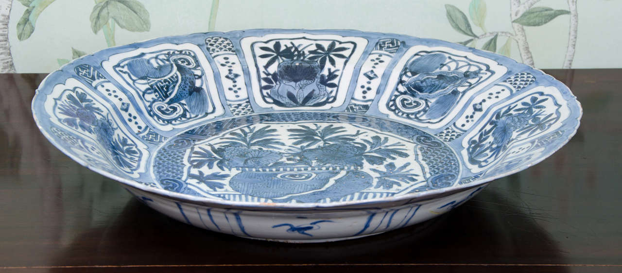 A large Chinese blue and white kraak charger, Wanli (1573-1619), decorated in the centre with a jardinière with plants and flowers. The panelled border decorated with flowers and precious objects. Good solid deep blue glaze. Condition: Consolidated
