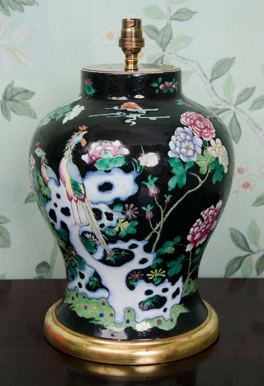 A beautiful Chinese porcelain Famille Noire baluster vase decoratd with phoenixes, rockwork, peonies and flowers. This vase dates from ca. 1840-1850 and is in excellent condition. The vase has been mounted on a hand carved water gilt wooden base and