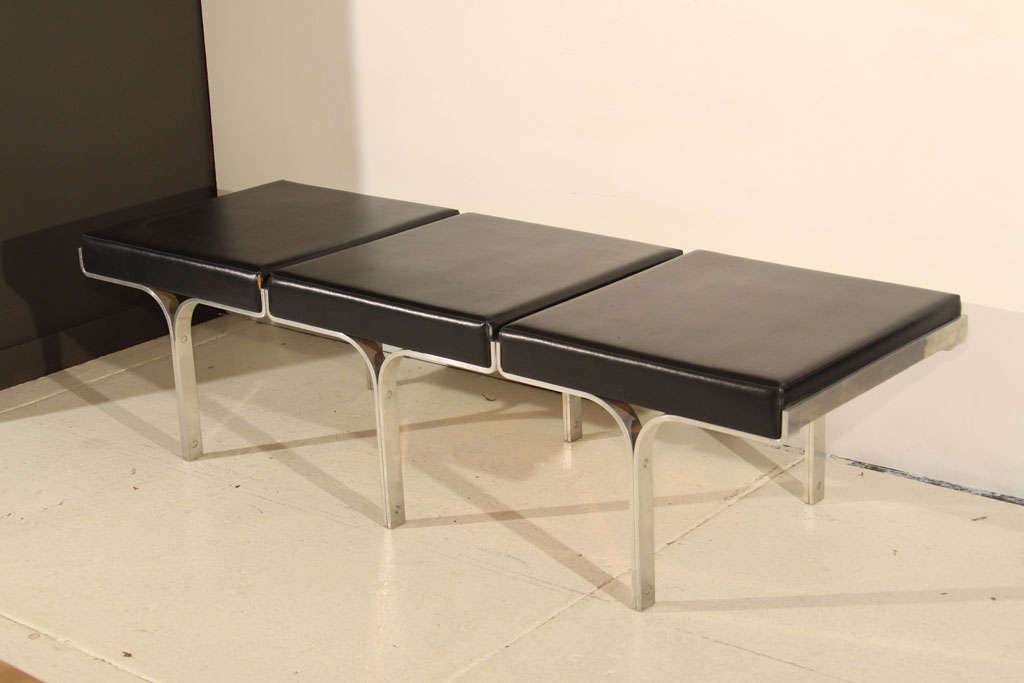 This three cushion modern bench features clean lines and an arch-themed base. This piece is included in the permanent collection of MOMA.