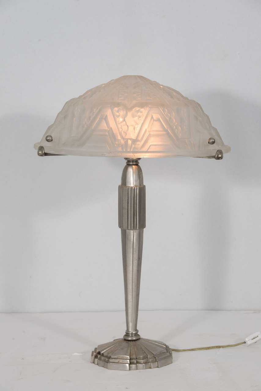 1920s, French Art Deco table lamp with signed, molded glass shade, on an architecturally inspired polished nickel finish over bronze. Signature is 