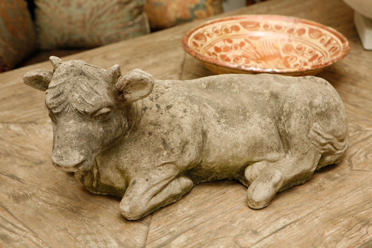Beautiful patina covers this delicately detailed cast stone sculpture of a reclining calf.