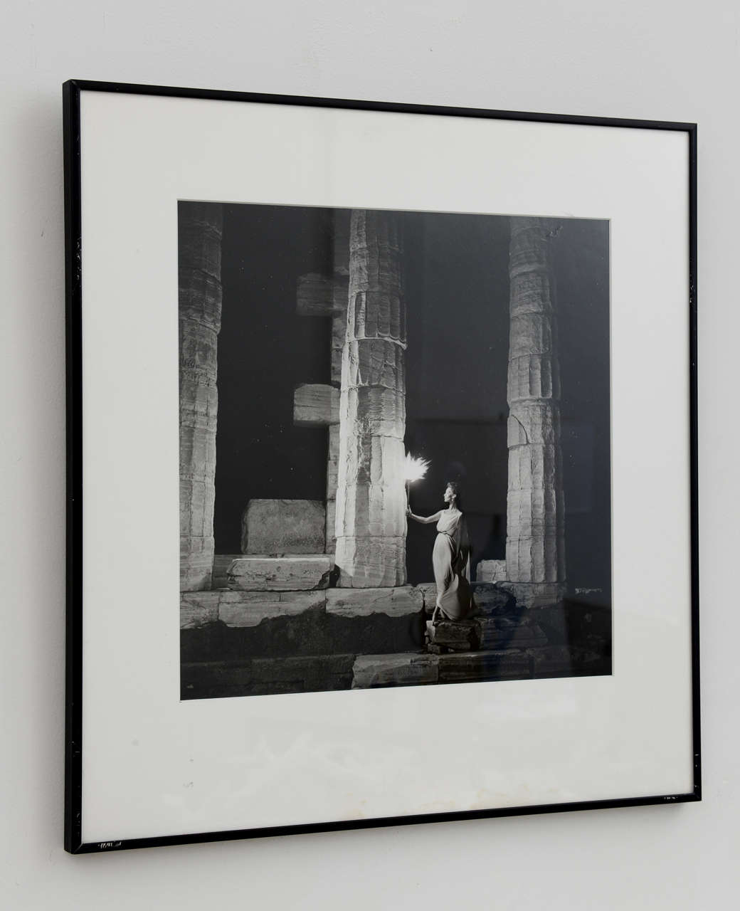 Black and white photograph entitled "Model at a Temple". 
Sliver gelatin print of model Ruth Newman in white Grecian-style dress at the Parthenon. Shot for the 1959 European winter collections for Harper's Bazaar and signed by the artist