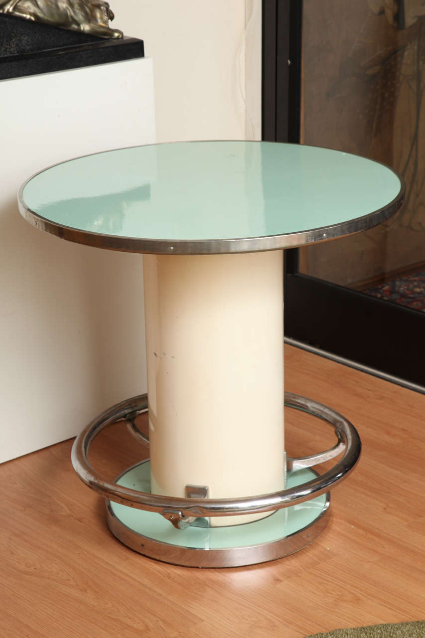 Jules Leleu (1883-1961).
Modernist circular pedestal table, with green lacquered tray top resting on a beige painted drum, with chrome footrest, 1950's. Model illustrated on page 94 in "Leleu: Decorateurs Ensembliers" by Francoise Siriex