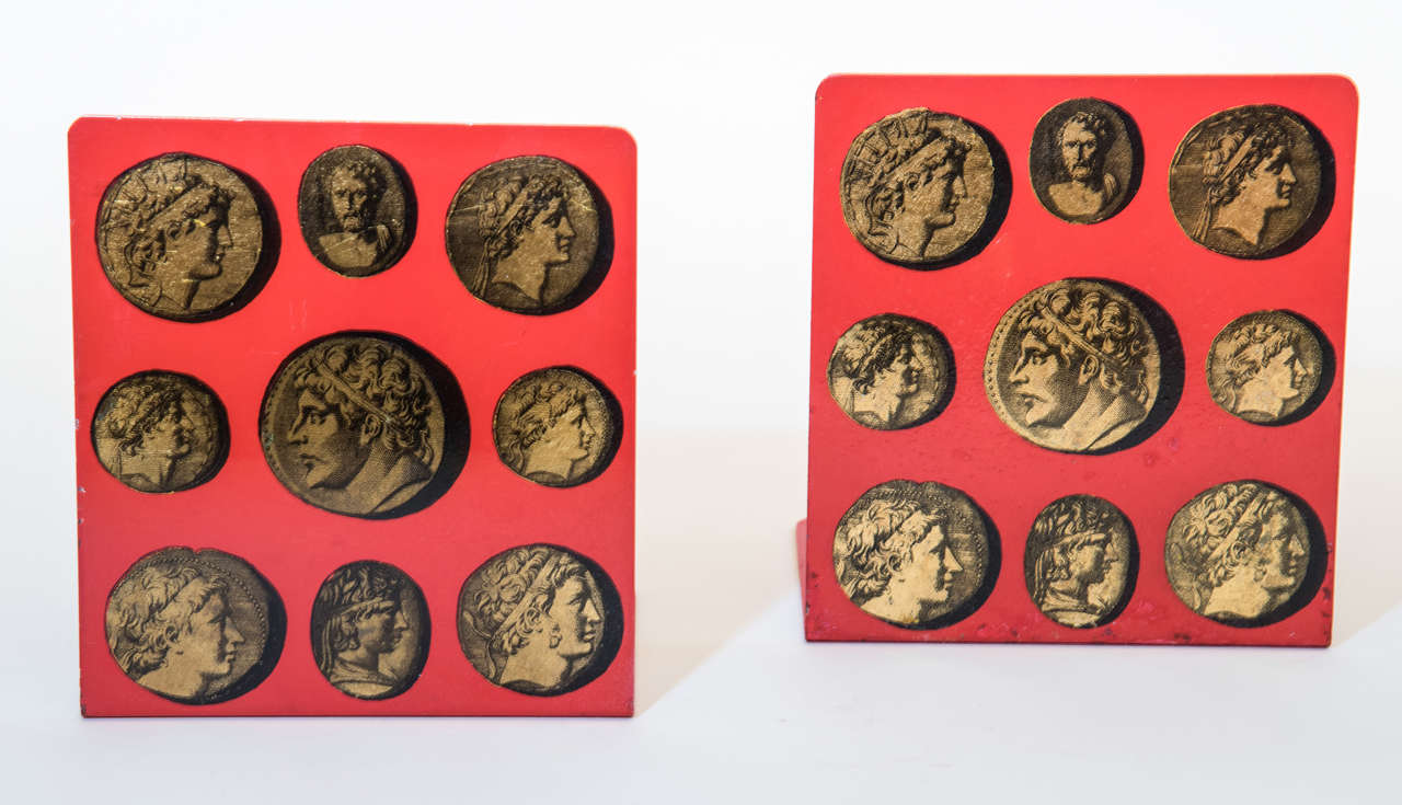 A brilliant pair of red bookends with classical bust motif details in gold by renowned designer Piero
Fornasetti.