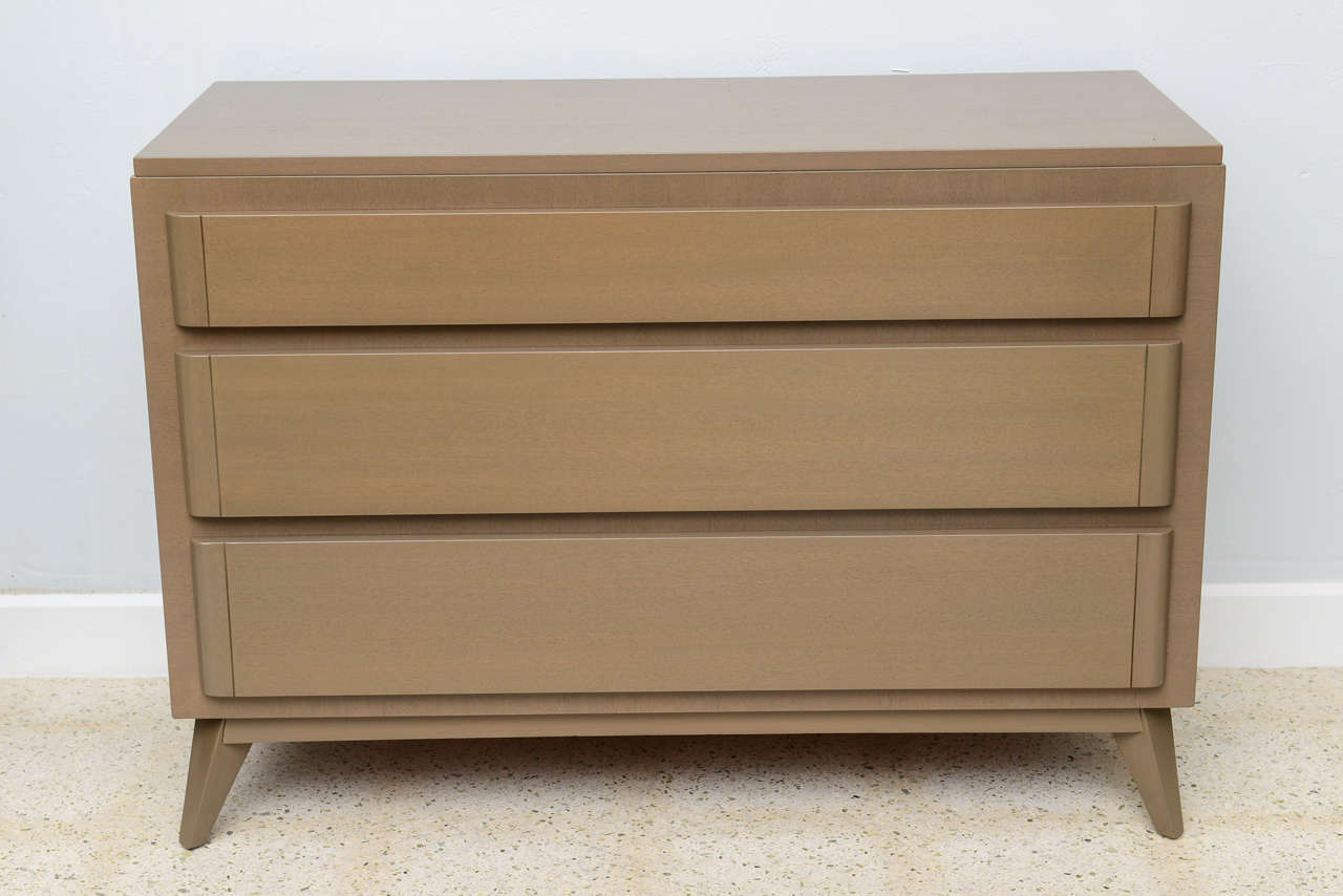 The rectangular top above three drawers with rounded edges, on splayed tapering short legs.
Manufactured by R- Way Furniture company.