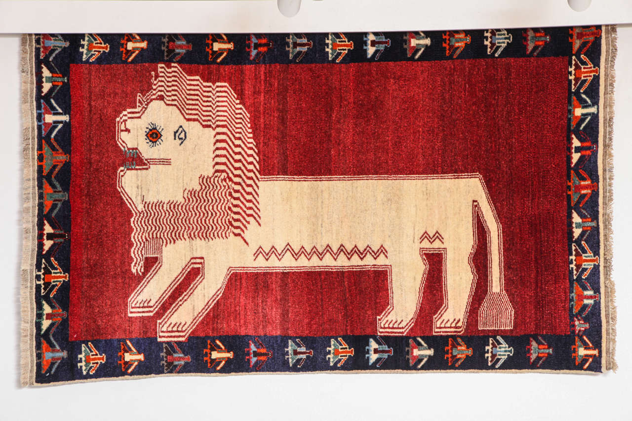 This Persian Qashqai carpet circa 1940 was created using a wool warp, wool weft, hand-knotted pure wool pile and natural vegetable dyes. The central lion design is rather striking in the way it contrasts the carpet's red field, as well as in its