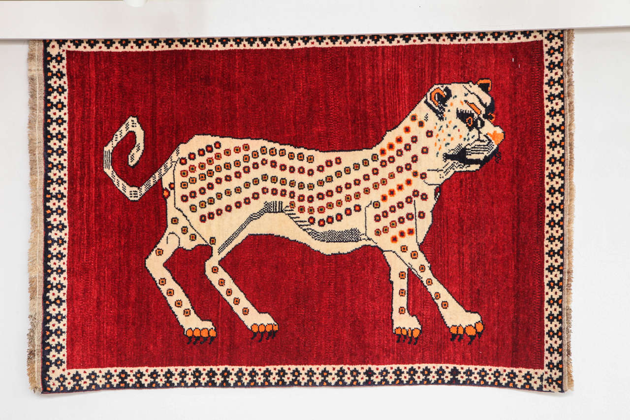 This Persian Qashqai carpet created circa 1940 consists of a handspun wool warp, weft and pile and natural vegetable dyes. The vibrant red field accentuates the striking image of the carpet's central leopard, completed in beige with black and orange