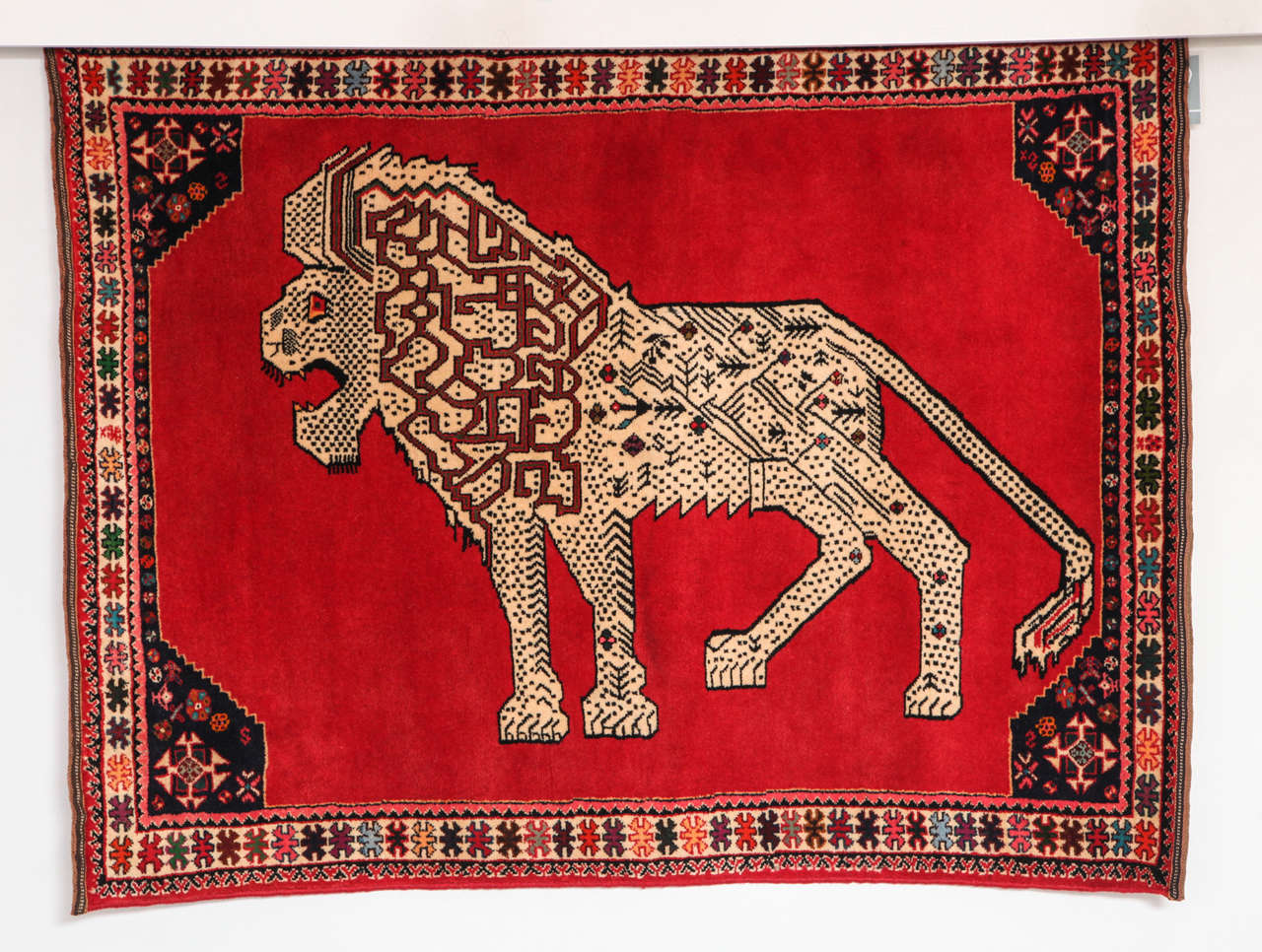 This Persian Qashqai carpet created, circa 1940 consists of a handspun wool warp, weft and hand-knotted pile and natural vegetable dyes. Its highly detailed central lion design is balanced by the carpet's strong red field and colorful geometric