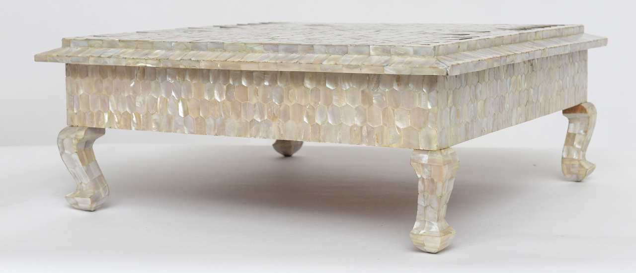 We love this unusual low table that shimmers with individually faceted mother-of-pearl tiles set within a grid of inlaid brass. Use as a low side table, a tabletop riser, or nestled under a coffee table.