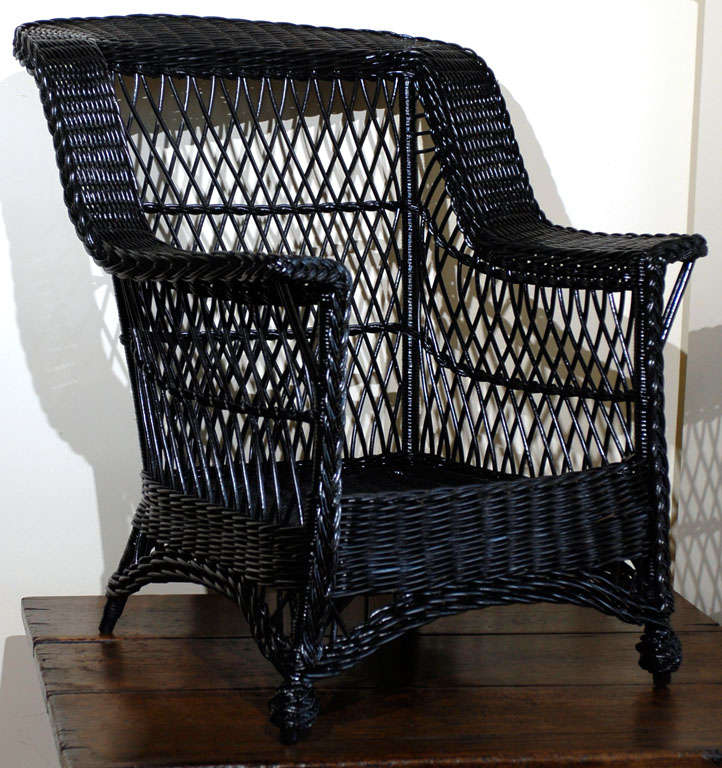 This is a handsome wicker chair.  The front feet are in the pineapple style.  A braid starts at one of the pineapple feet and leads up around the chair to opposite foot.  The lines are handsome and the chair is comfortable. This is a wonderful piece