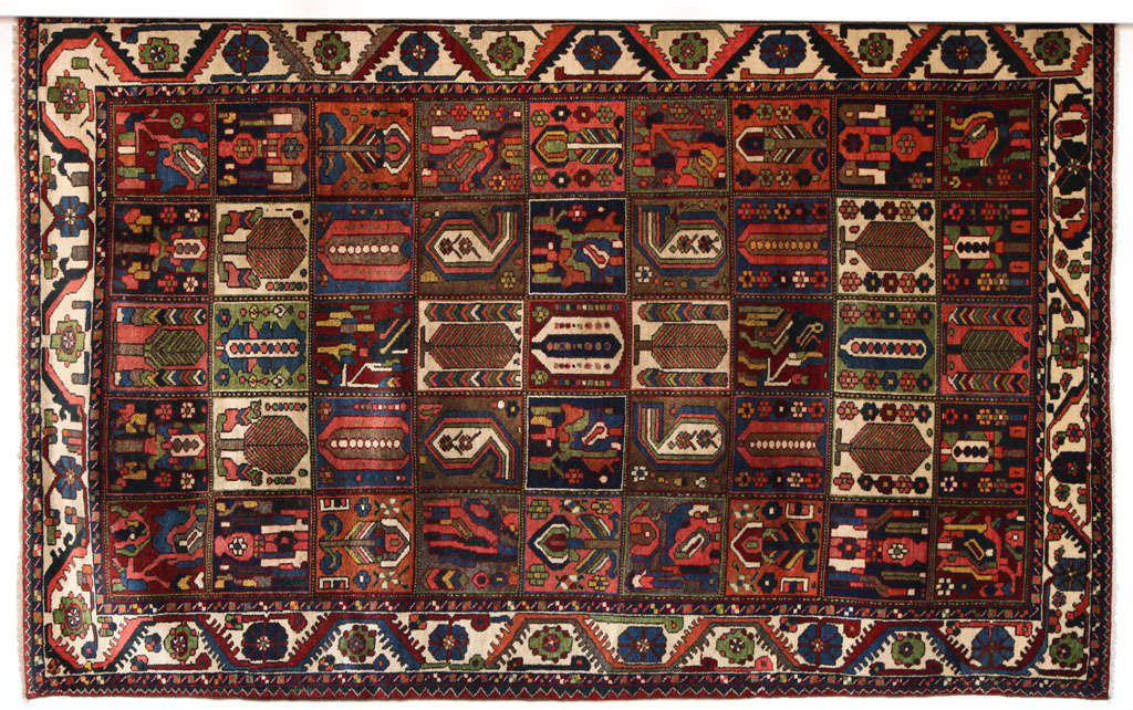 This Persian garden design Bakhtiari carpet in handspun wool and vegetable dyes showcases a fluid yet geometric composition with earthy colors of blue, green, cream, deep red and navy. The size is 7'1