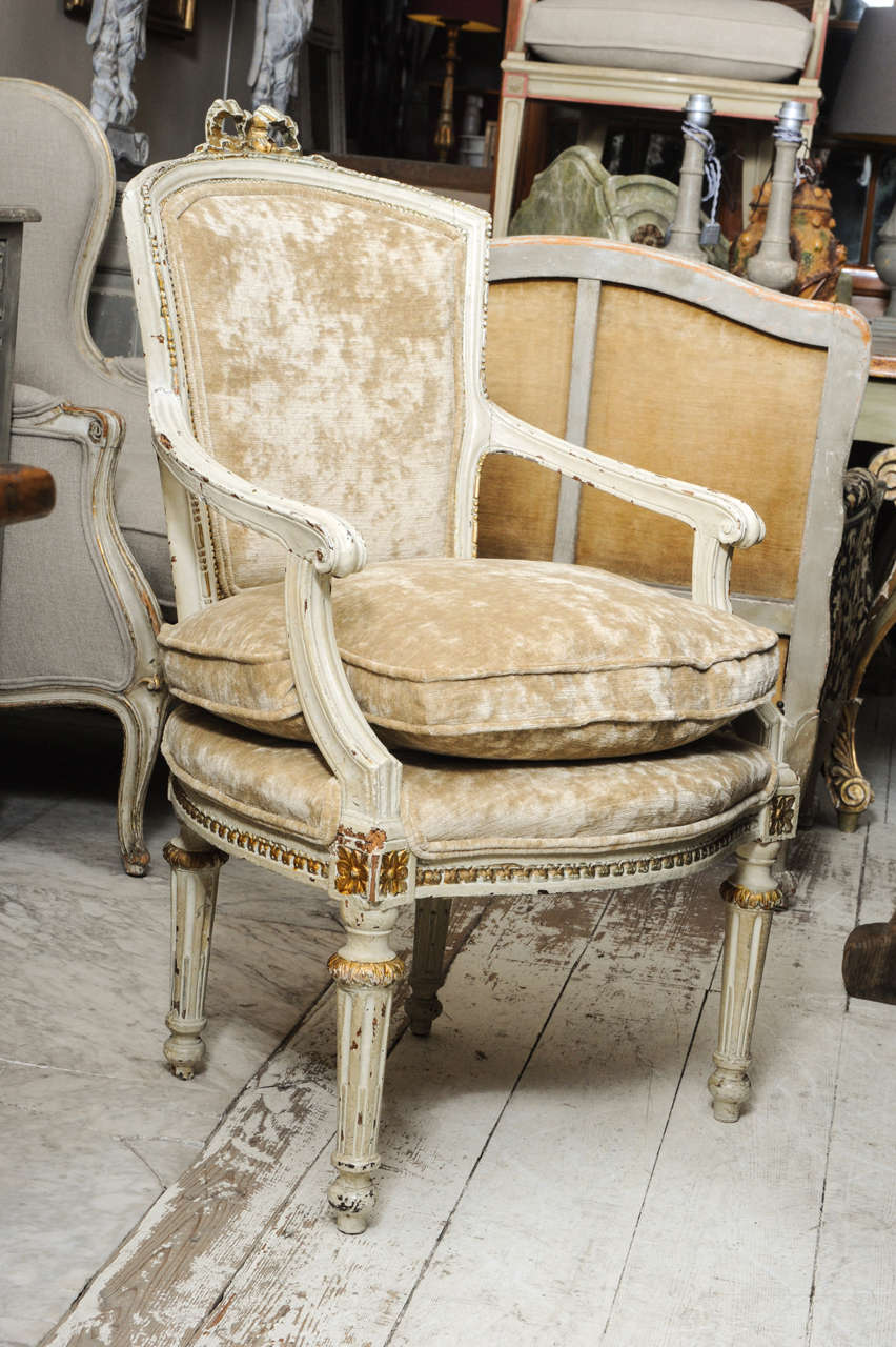 A Pair of early Louis XVI Armchairs, coloured in Ivory, with golden details. The fabrique is gold coloured, with a velvet linen look