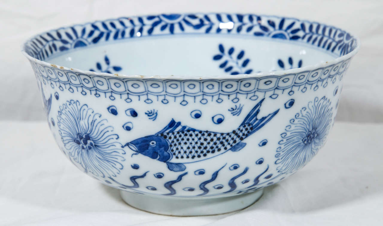 A Chinese blue and white porcelain bowl of slightly everted rim, deep form supported on a short foot rim and decorated with koi fish* to exterior and interior. The exterior shows koi and aquatic plants below a geometric design along the rim. The