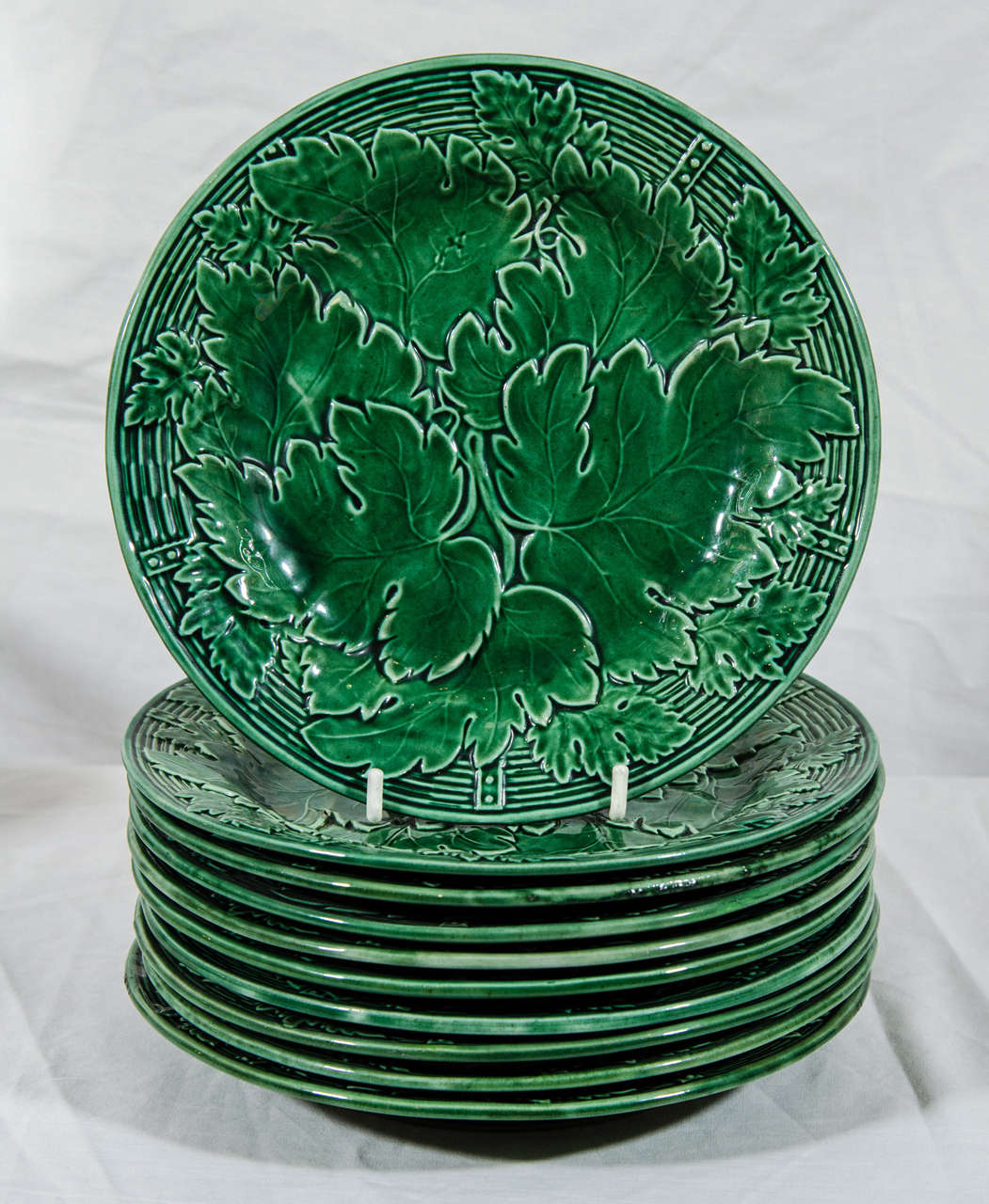 A set of a dozen 19th century English Majolica plates made by Davenport. The detailed design features large impressed oak leaves colored with a light green glaze. The reverse marked with the impressed Davenport anchor.