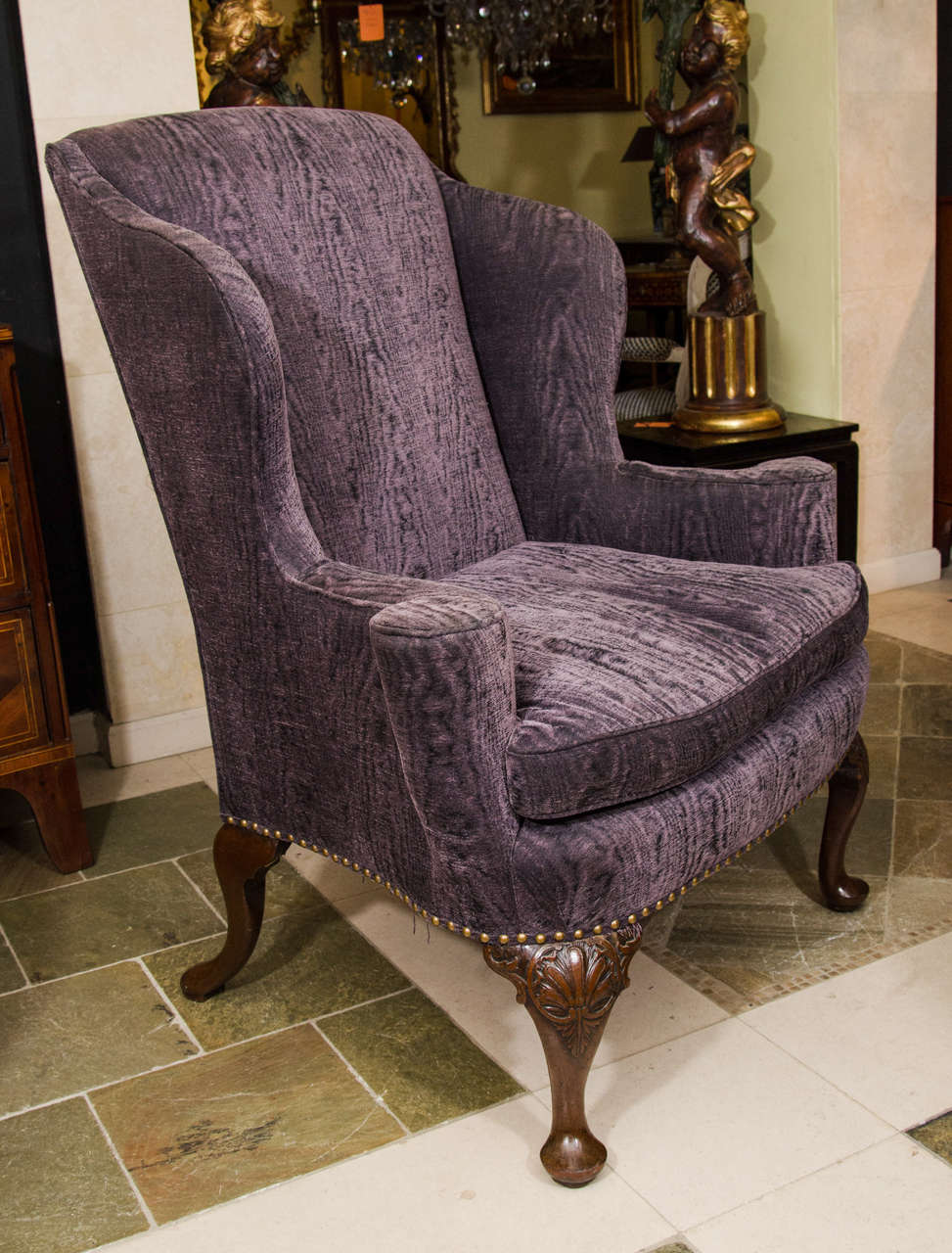 George II walnut wing chair with outscrolled arms and punchwork shell decorated cabriole legs ending in pad feet.