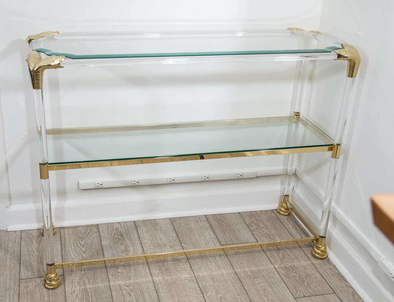 Lucite and brass étagère featuring snake head details and glass shelves.