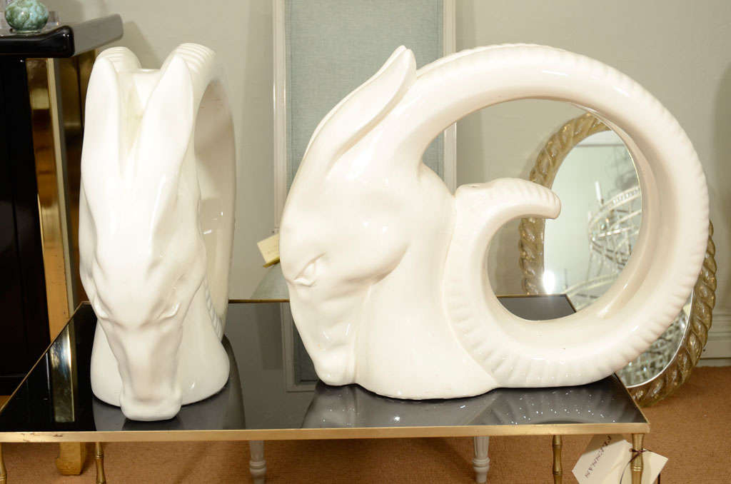 This graceful pair of cream colored porcelain rams head are sculptural gems with a versatile decor style.  Punctured holes through center of each head allow for easy conversion to lamp bases.  They could also be easily turned into a table base.