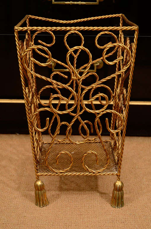 Decorative scrolled footed vessel has tasseled footed legs and open rope scrolled details.  May be used as waste basket, umbrella stand or magazine bin.