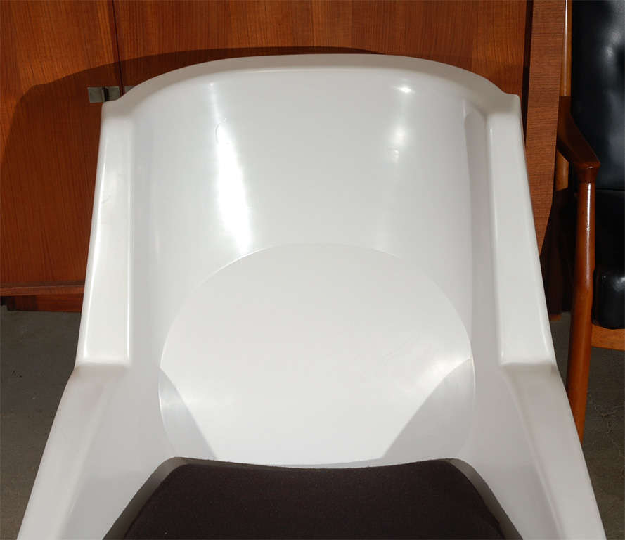 Chaise longue en plastique blanc avec coussin d'assise rembourré noir et base en métal. Impressionnée et datée Strassle International.