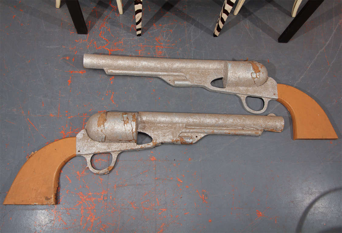 pair of oversized pistols from 1960's float from celebration in southern Texas.  these are great in person- photos do not do them justice. wood frames with paper, paint and traces of burnished german glass on the barrels.