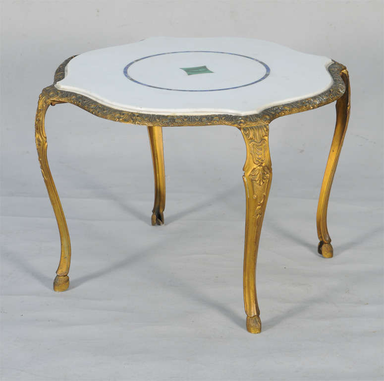 Accent table, having a free-form top of pure-white makrana marble inlaid with lapis and malachite, on finely chased base of gilt bronze, raised on cabriole legs with hoofed feet.