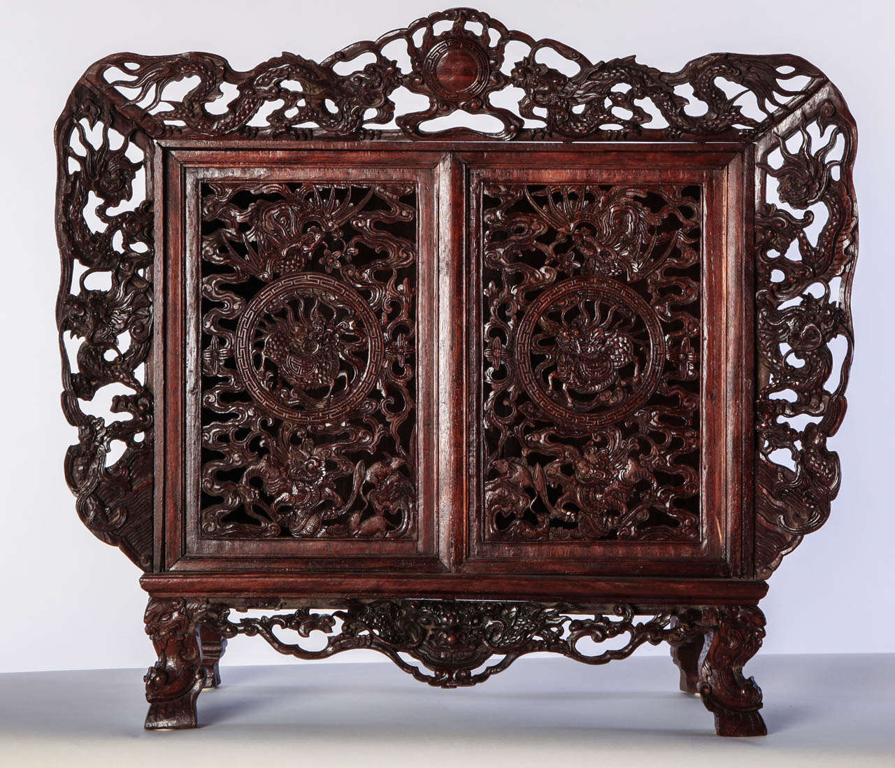 A SMALL OPENWORK WOOD CABINET DEPICTING DRAGONS, China 
Size	61x67x25 cm