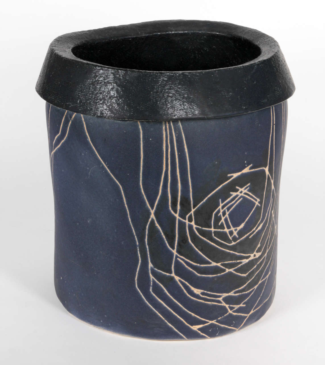 LUKE LIETZKE (1906-2000), USA
LIETZKE DESIGNS   Mogodore, Ohio

Large floor vessel c. 1955-1960

Blue glazed stoneware cylindrical vessel which has been shaped at the top into an elliptical form; the black glazed lip is rolled over with a
