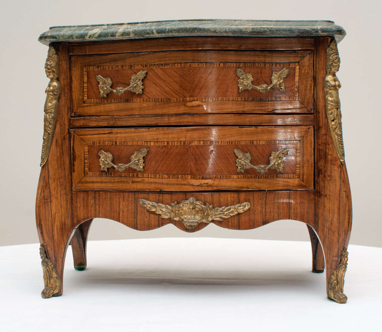 A Fine French 19th c. Louis XV style Kingwood Parquetry Inlaid miniature bronze mounted two drawer commode, having a shaped Green marble top above a conforming case with two bookmatch parquetry inlaid drawers, the sides similarly inlaid, shaped