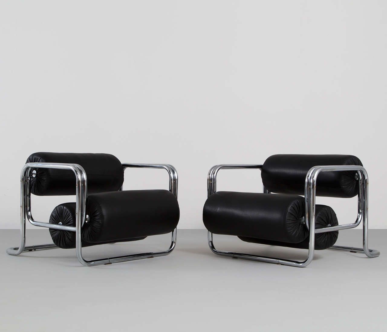 Pair of easy chairs, in steel and leather, Germany 1960s. 

Interesting pair of tubular armchairs with black leather upholstery. The frame consist of bended tubular steel. Seating and back are made of large 'rolls' upholstered in leather. The