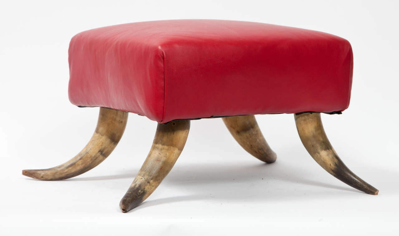 This small stool in red leather and horn legs is perfect as an accent piece, as a foot stool or for books and magazines.