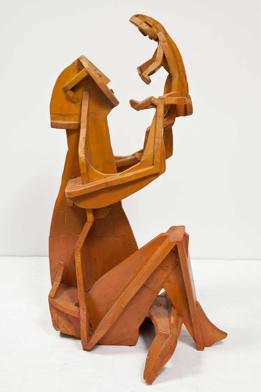 Une sculpture en bois peinte et signée représentant une mère et son enfant, belle dans sa pureté et sa simplicité.