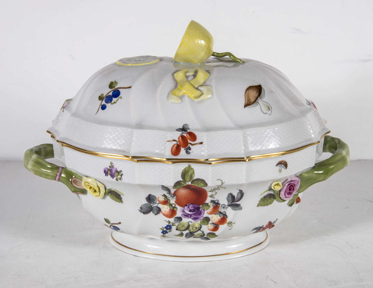 This mint condition tureen features hand painted detailing of flowers, fruit, and insects. It also has stylized asparagus handles and a lemon atop the dome serves as a handle. The tureen is trimmed in 24k yellow gold and is marked Herend, Hungary on