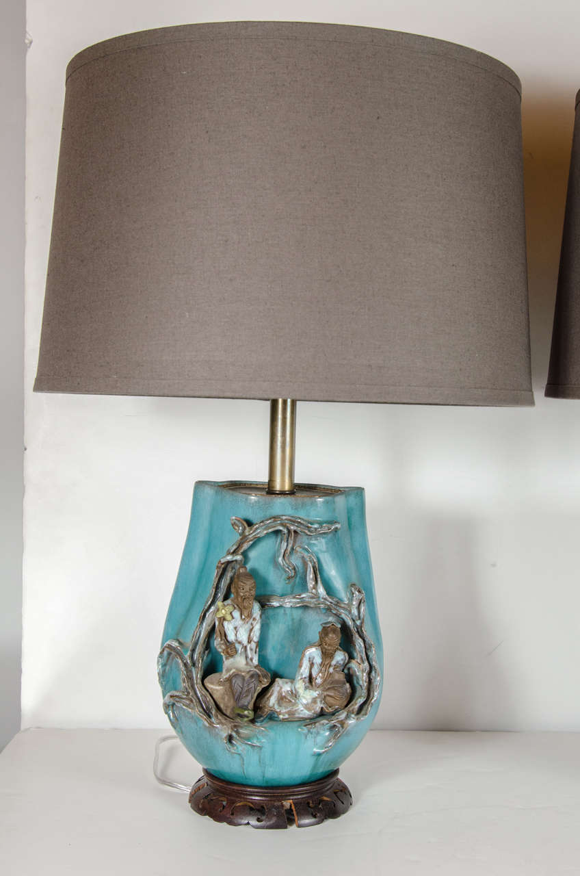 This exquisite lamp depicts an ancient Chinese scholar scene that has been hand-painted and studio made. It depict ancient Chinese scholars in a polychromed finish on an urn form of a rich celadon glaze. It is fitted with hand-carved Chinese style