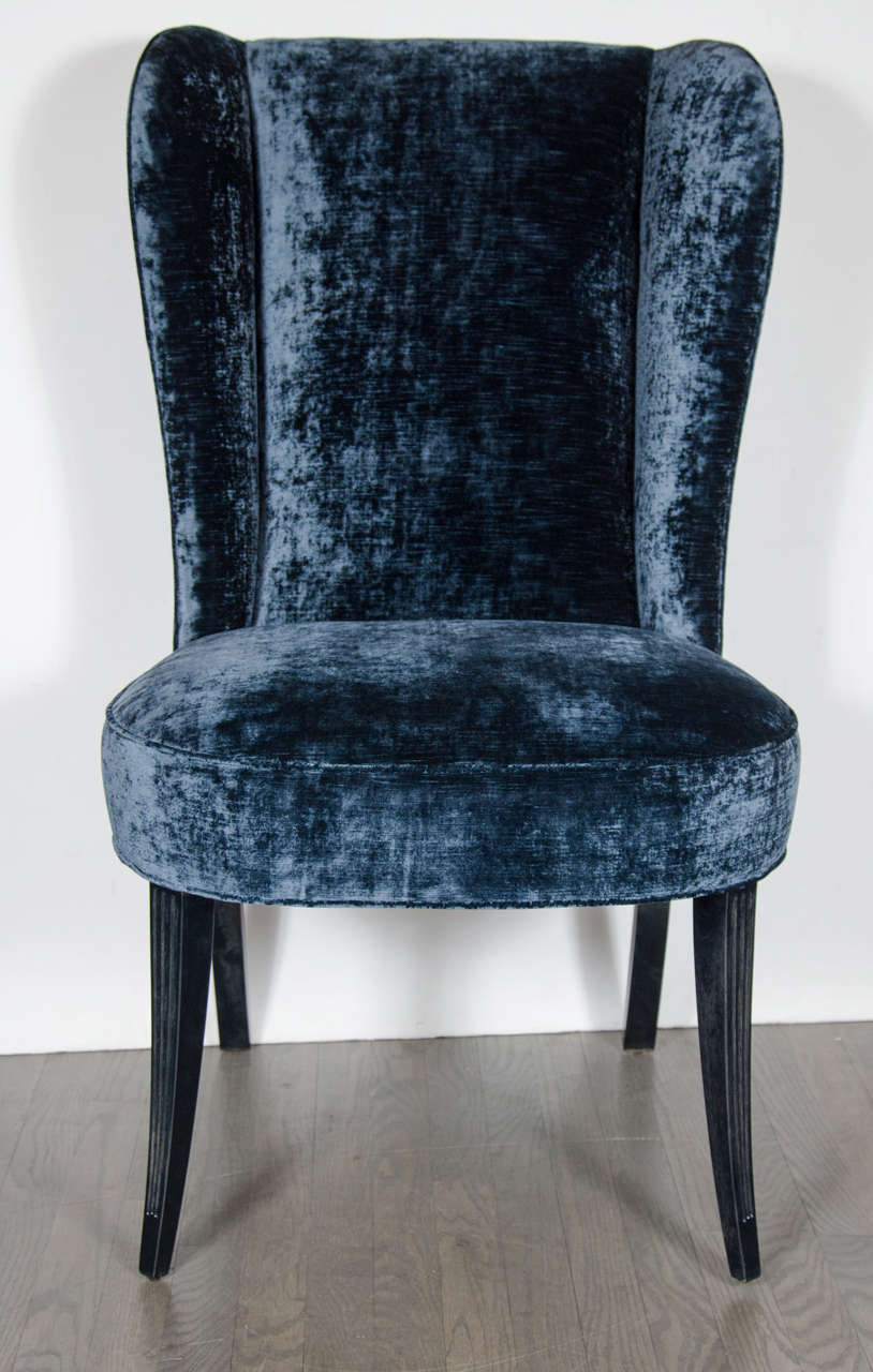 This gorgeous pair of chairs feature stylized scroll form wingback design and ebonized walnut legs. They have been newly upholstered in a rich sapphire blue velvet. These chairs have been mint restored.