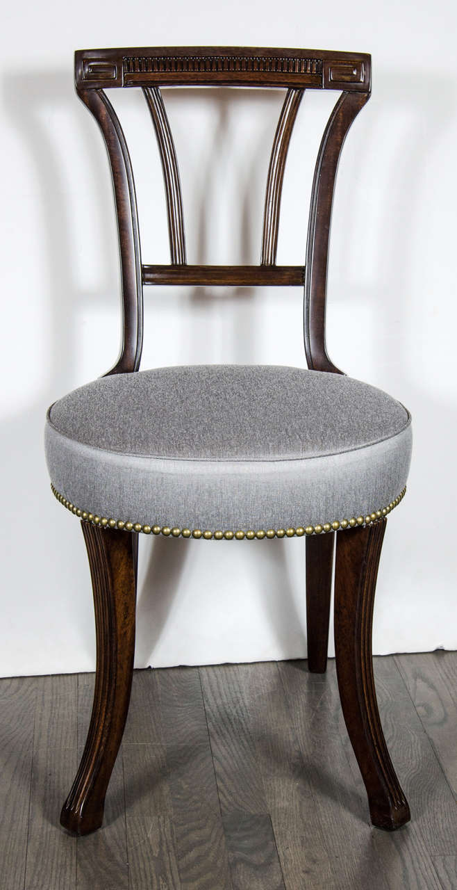 This pair of sophisticated 1940s Hollywood occasional chairs by Grosfeld House features a rounded seat in new silver metallic sharkskin upholstery and stud detailing, an ebonized walnut frame with square footed fluted sabre legs and cut-out back
