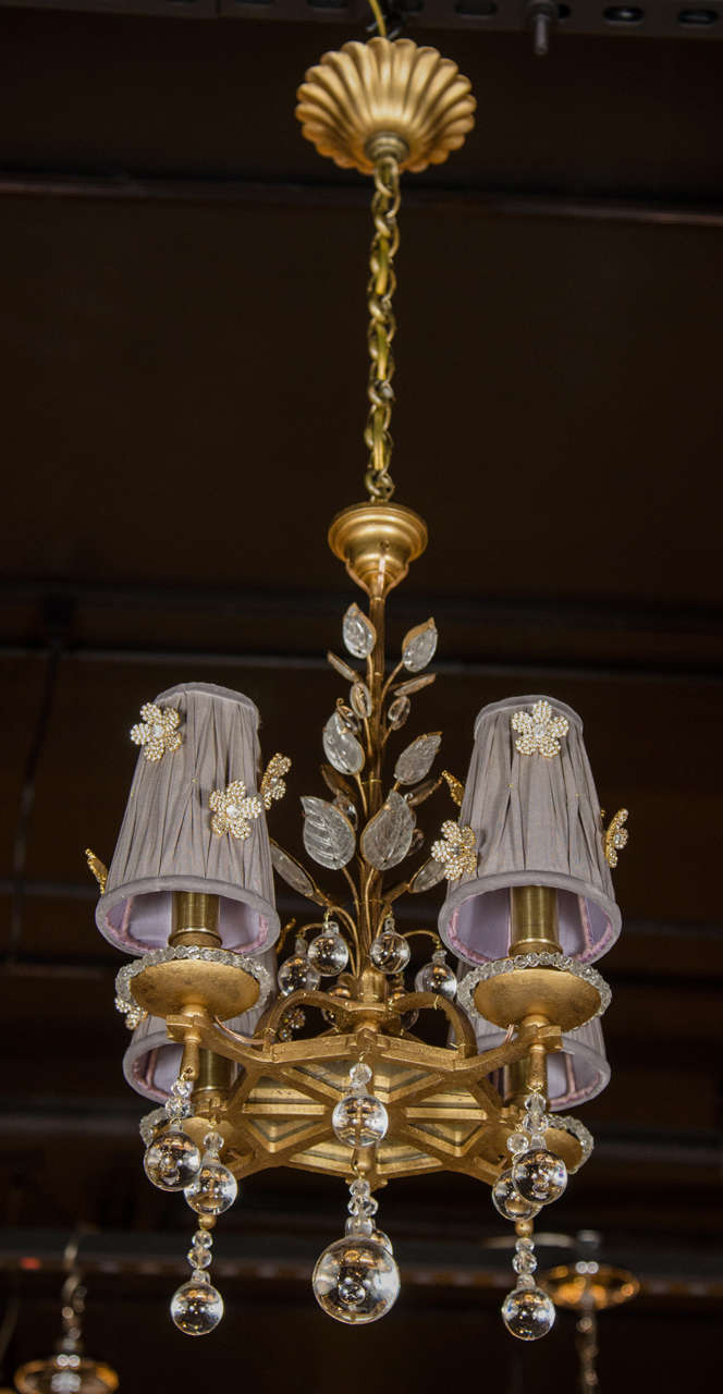 This elegant chandelier is gilded bronze decorated with stylized foliage crystal detailing and beadwork. It also features glass ball pendants, inset antique mirror panel accents and four lights fitted with custom silk shades. It has been newly